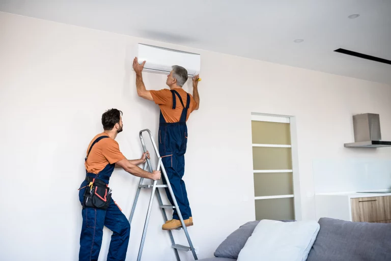 Zwei Klimatechniker bringen eine Klimaanlage nachträglich in einer Wohnung an
