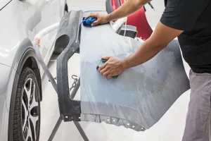 Werkstatt Mitarbeiter schleift einen Kotflügel ab um diesen zu lackieren