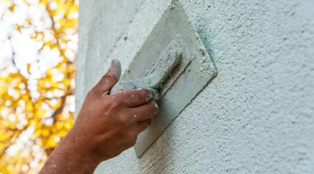 Maler bringt mit einer Spachtel Außenputz an eine Fassade an