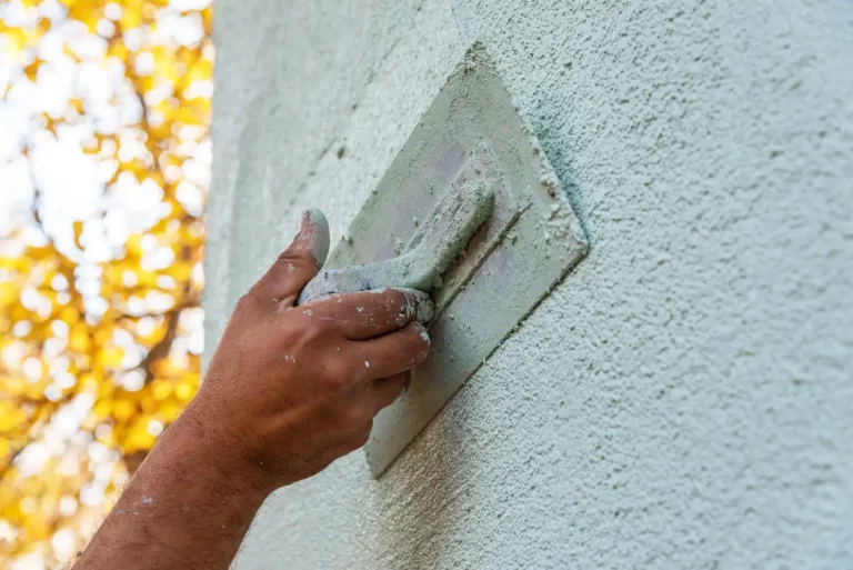 Maler bringt mit einer Spachtel Außenputz an eine Fassade an