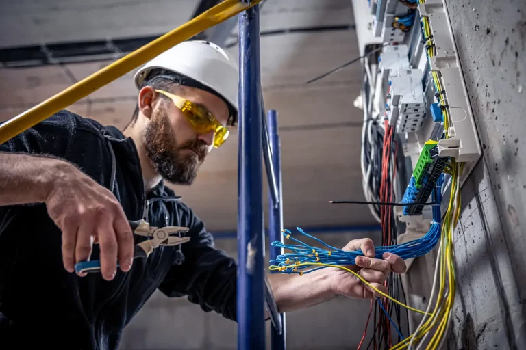 Elektriker schließt im Rahmen einer Elektroinstallation Kabel an einer Schalttafel an