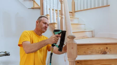 Schreiner montiert mit einer elektrischen Nagelpistole ein neues Treppengeländer aus Holz