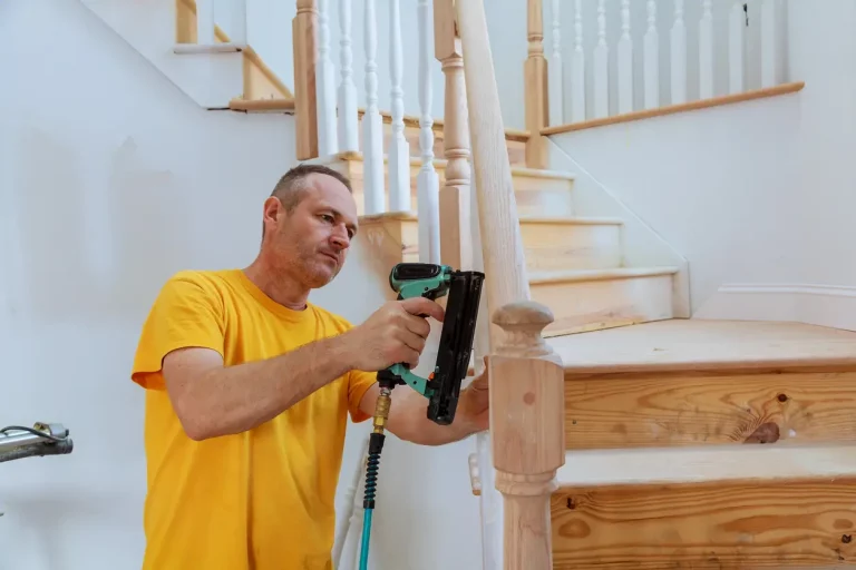 Schreiner montiert mit einer elektrischen Nagelpistole ein neues Treppengeländer aus Holz