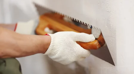 Maler bringt mit einer Putzspachtel Sanierputz an einer Kellerwand an