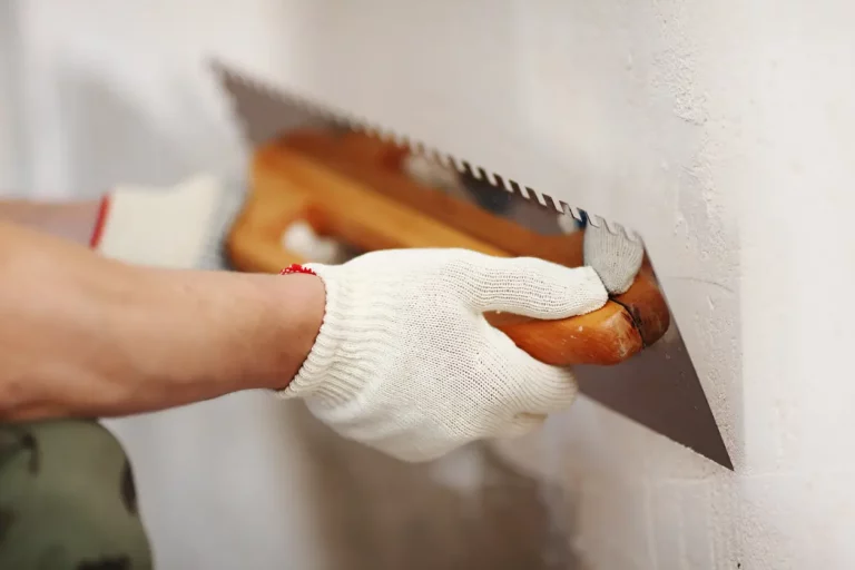 Maler bringt mit einer Putzspachtel Sanierputz an einer Kellerwand an