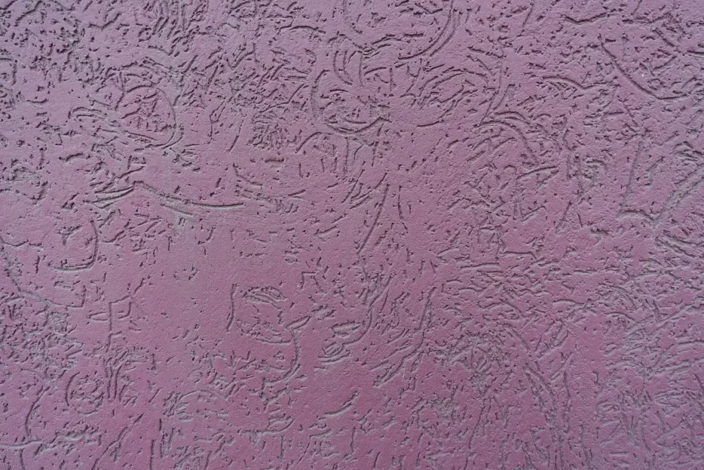 Nahaufnahme von lila farbigen Wurmputz an einer Außenfassade