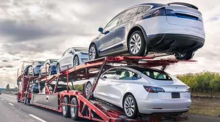 Autotransporter mit mehreren PKWs auf einem Anhänger bei der Fahrzeugüberführung auf einer Landstraße