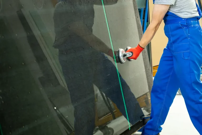 Glaser hebt mit professionellen Saugnäpfen eine Glasscheibe für den Austausch von Fensterscheiben hoch