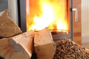 Brennender Hybridofen mit Holzscheit und Pellets im Vordergrund
