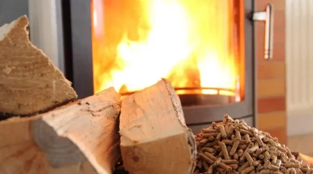 Brennender Hybridofen mit Holzscheit und Pellets im Vordergrund
