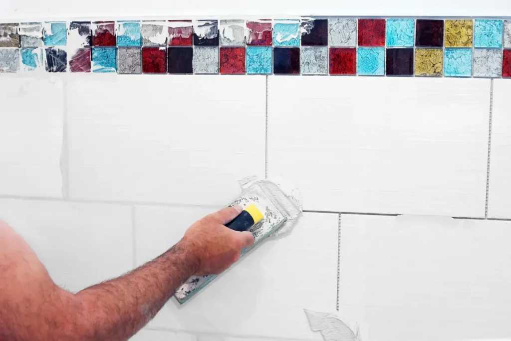 Fliesenlegermeister bringt Fugenmasse auf Mosaikwandfliesen auf