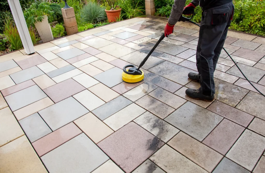 Handwerker reinigt Terrassenplatten aus Naturstein mit einem Hochdruckreiniger