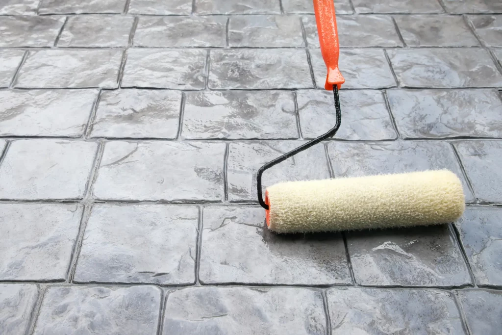 Mittel zur Versiegelung der Terrasse wird mit einer Malerrolle auf Terrassensteinboden aufgetragen