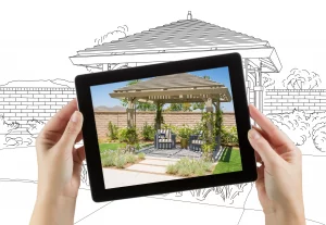 Weibliche Hände halten ein Tablet Tablet mit Foto von einer Terrasse mit Pergola im Rahmen einer Terrassenplanung