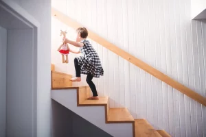 Junges Mädchen mit Kuscheltier läuft breite Treppenstufen ohne Treppensicherung nach oben
