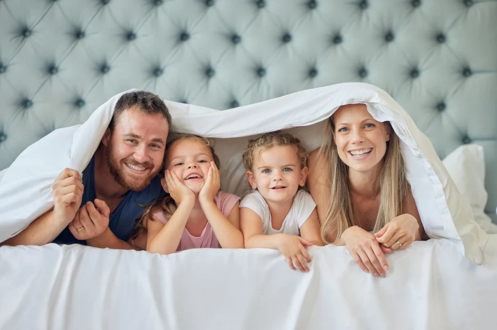 Familie mit Vater, Mutter und zwei Kindern im Bett unter der Decke
