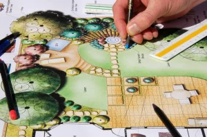Gartenarchitekt zeichnet mit Buntstiften eine Skizze zur Gestaltung eines Gartens.