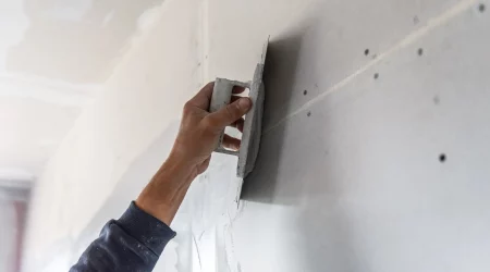 Maler bringt mit einer Kelle Grundputz im Innenbereich auf