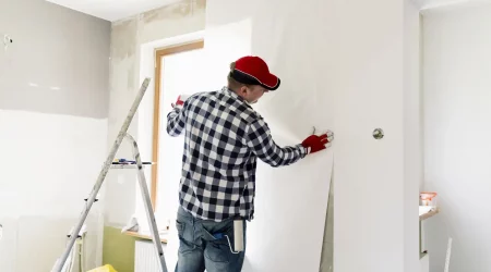 Maler bringt beim Tapezieren einer Wohnung Tapete an eine Wand an