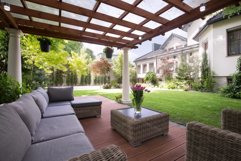 Eine mit Glas überdachte Terrasse mit Sitzgruppe in einem Garten