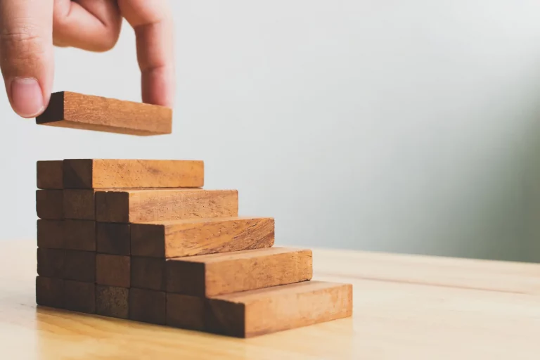 Zwei Finger schlichten kleine Holzklötze zu einer Treppe
