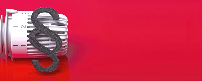 Heizkörper Thermostat vor einem roten Hintergrund mit einem Paragraphen als Zeichen des beschlossenen Heizungsgesetz