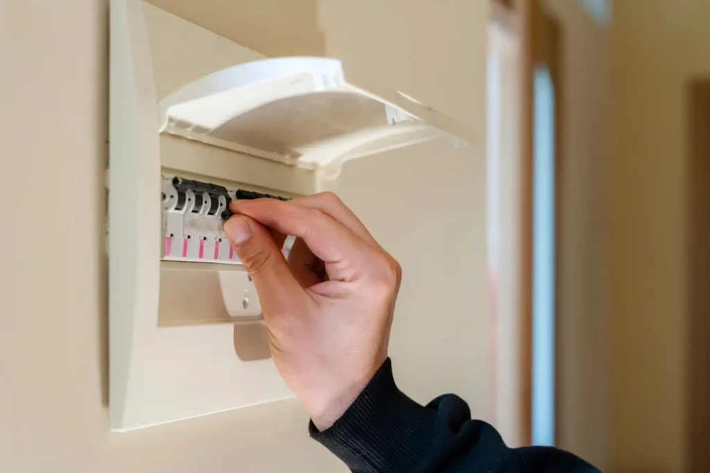 Männliche Hand schaltet den Strom in einem Haus an einem Sicherheitskasten aus
