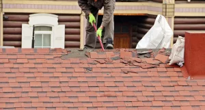 Dachdecker auf einem Dach mit Stemmeisen bei einer Dachreparatur