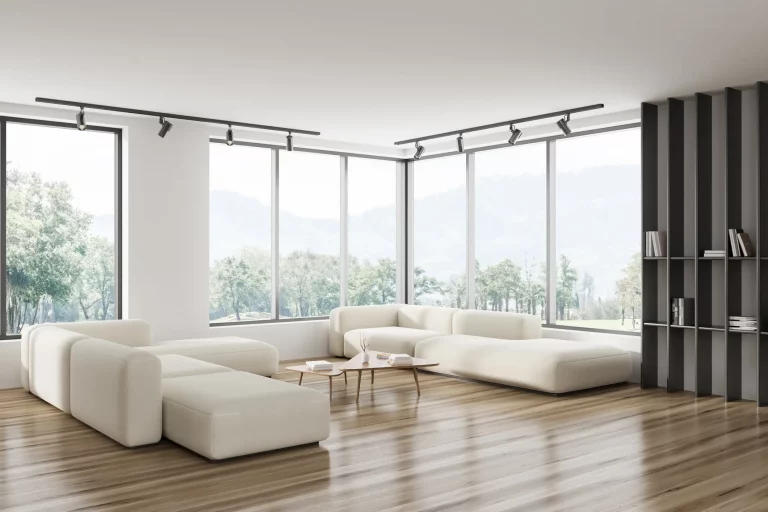 Bodentiefe Eckfenster in einer hellen modernen Wohnung mit einer beigen Sofasitzgruppe