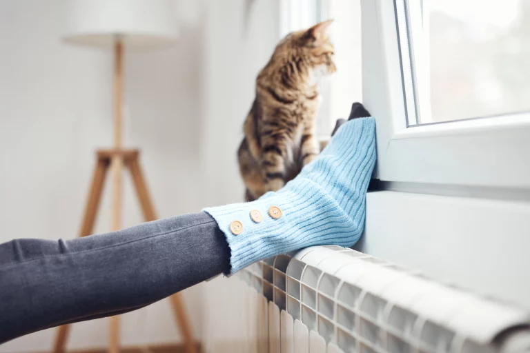 Frauenfüße mit Wollsocken auf Heizung