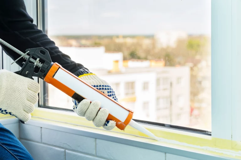 Arbeiter dichtet Fenster ab