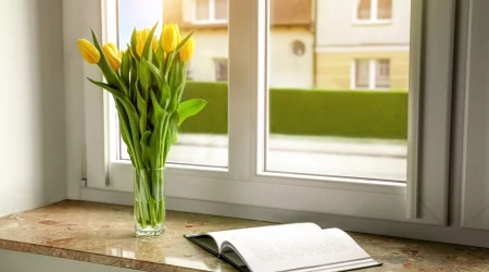 Blumenstrauß und Buch auf einer inneren Fensterbank