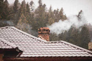 Ein qualmender Schornstein auf einem Haus im Winter mit Rauch eines Kaminofens