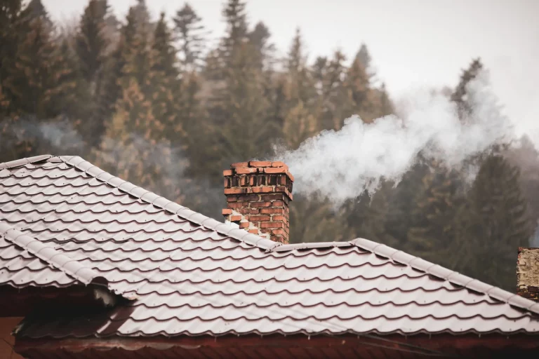 Ein qualmender Schornstein auf einem Haus im Winter mit Rauch eines Kaminofens