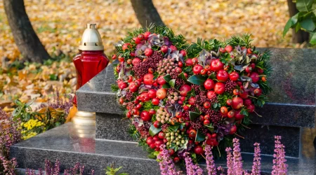 Gepflegtes Grab mit einem Blumengesteck und einer Kerze