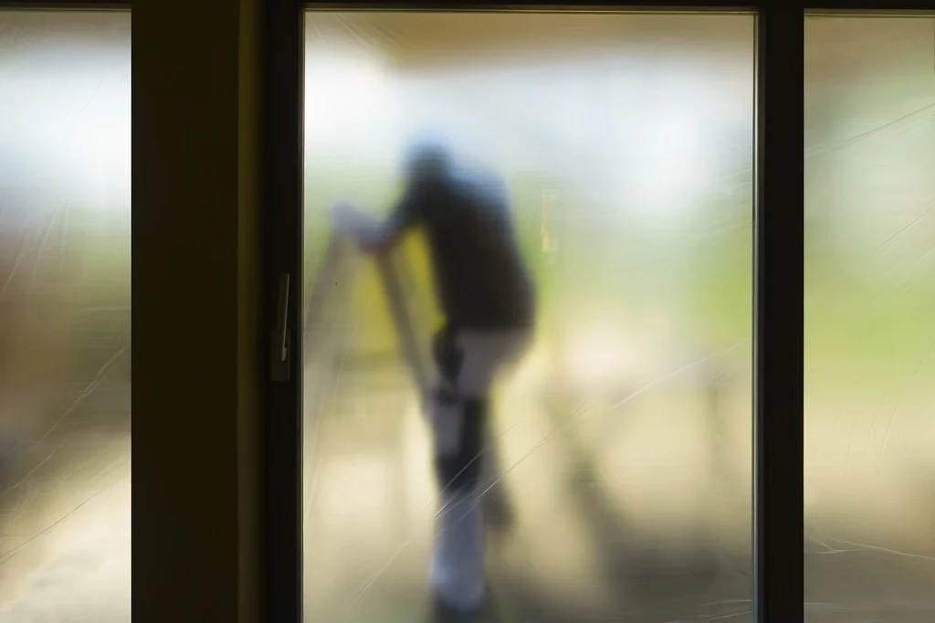 Maler befestigt Sichtschutzfolie am Fenster