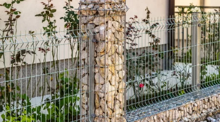 Stahlgitterzaun aus Draht mit Gabionen, die mit Natursteinen befüllt sind