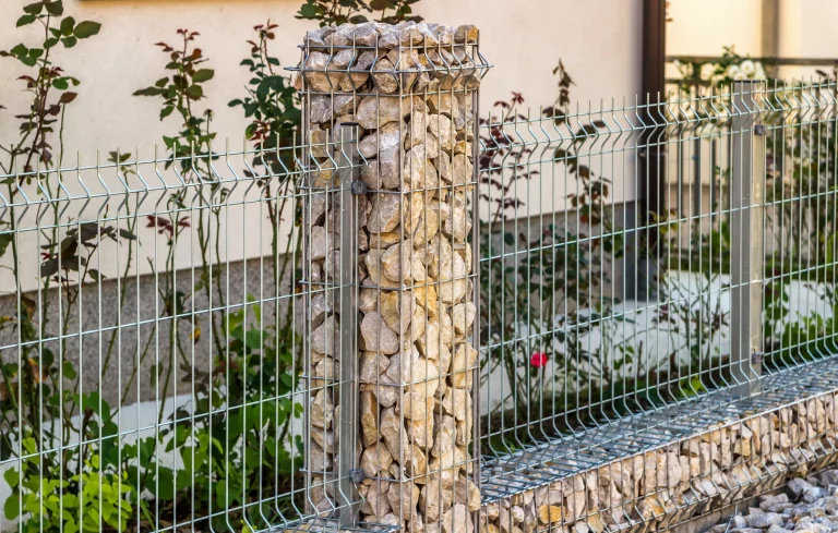 Stahlgitterzaun aus Draht mit Gabionen, die mit Natursteinen befüllt sind