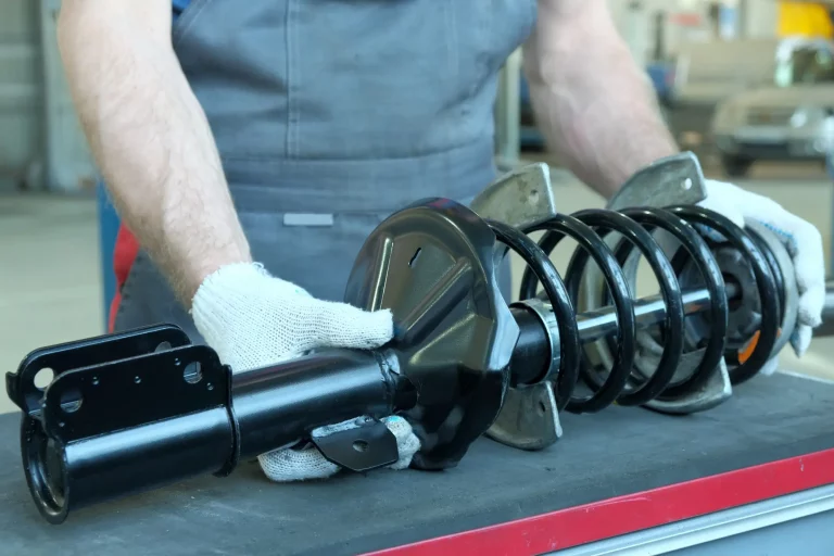 Ein Werkstattmitarbeiter bereitet einen neuen Stoßdämpfer für die Installation während der Reparatur und Wartung des Autos vor