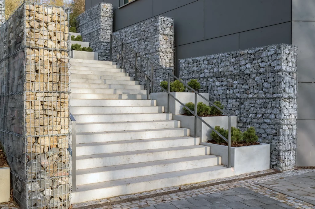 Moderne Betontreppe mit Gabionen als Treppenlauf