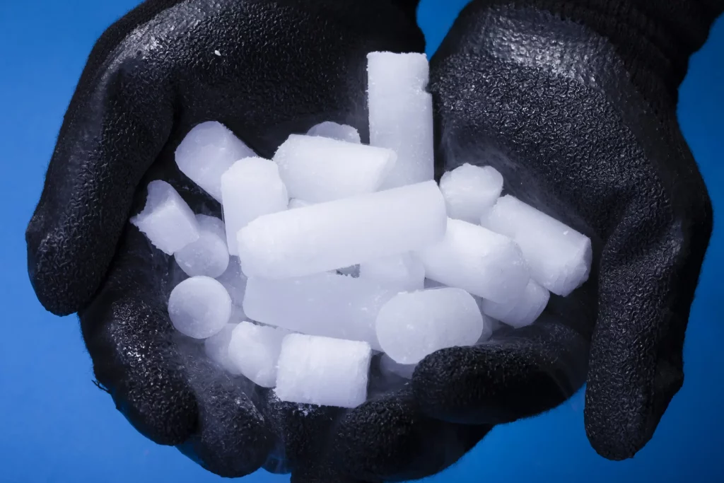 Trockeneis in Händen mit schwarzen Gummihandschuhen