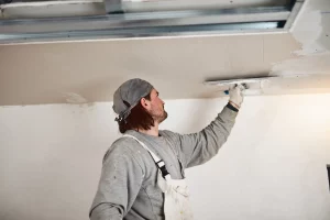 Maler verputzt mit einer Kelle eine Trockenbaudecke in einem Raum