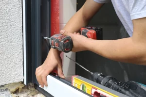 Fenstermonteur baut ein modernes Fenster mit Akkuschrauber und Wasserwaage – präziser Fenstereinbau im Neubau oder bei Renovierung ein.