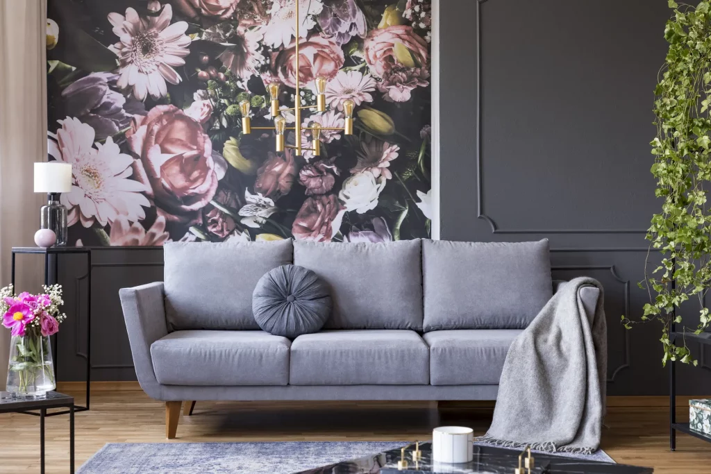 Fototapete mit bunten Blumen hinter einem graunen Stoffsofa in einem Wohnzimmer