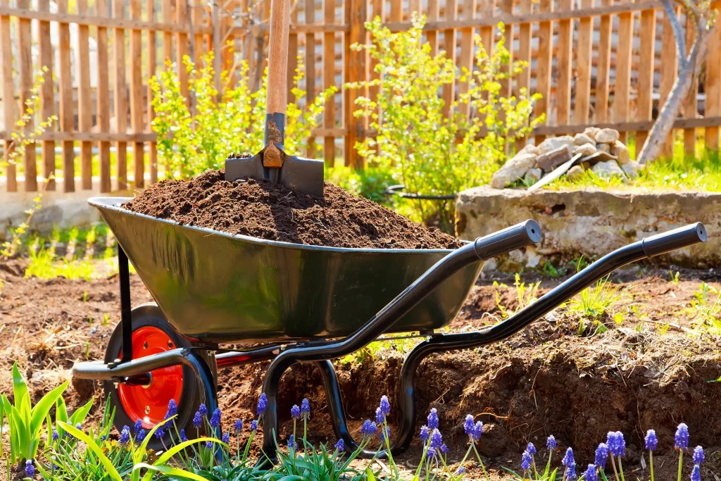 Schubkarre in einem Garten gefüllt mit Mutterboden Erde