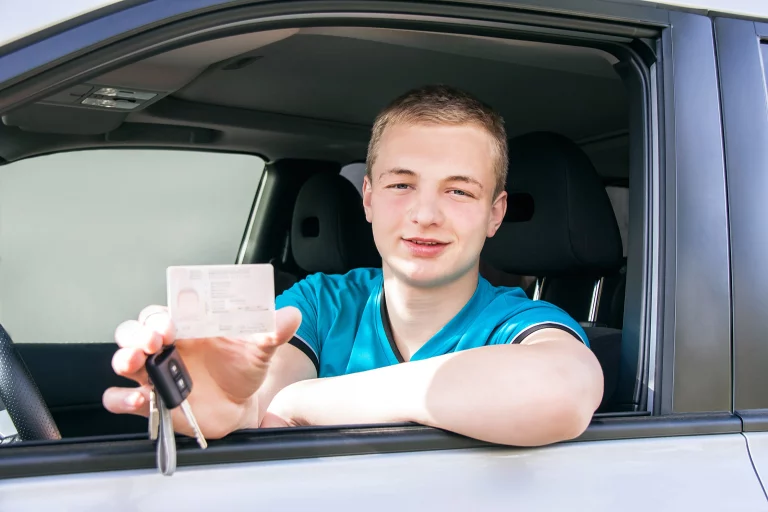 Junge in blauem T-Shirt hält seinen Führerschein in der Hand