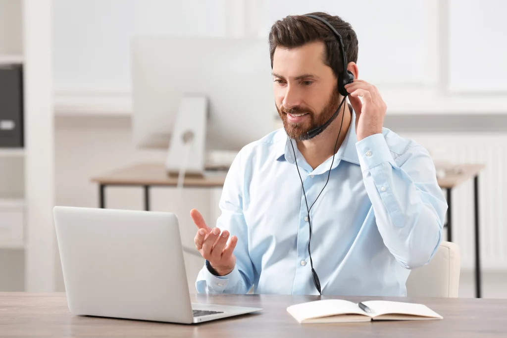 Mann mit Headset führt ein Kundengespräch über Laptop – symbolisiert eine effektive Kommunikation.