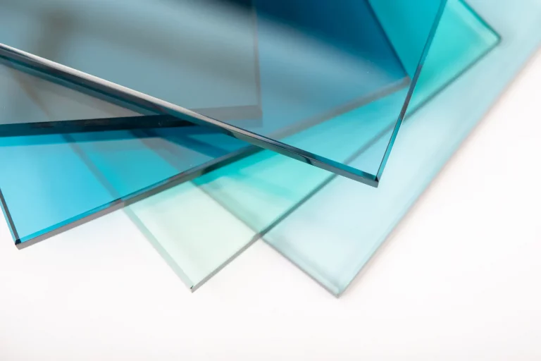 Mehrere leicht gestapelte, blaue und transparente Scheiben aus Einscheibensicherheitsglas (ESG) auf einem weißen Hintergrund. Das Bild zeigt die klare und robuste Beschaffenheit des Glases, das häufig für Türen, Fenster und Trennwände verwendet wird.