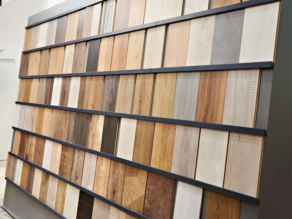 Ausstellungswand mit verschiedenen Holzlaminatplatten in unterschiedlichen Farben und Mustern. Die Platten sind in Reihen angeordnet und zeigen eine Vielzahl von Holzarten und -tönen von hell bis dunkel.