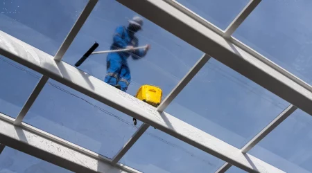 Reinigungskraft reinigt Glasdach